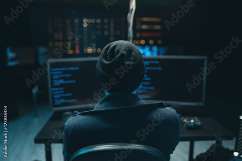 Dangerous Hooded Hacker Breaks into Government Data Servers and Infects Their System with a Virus. Hideout Place has Dark Atmosphere. Wanted programmer coding virus ransomware using computers. photo