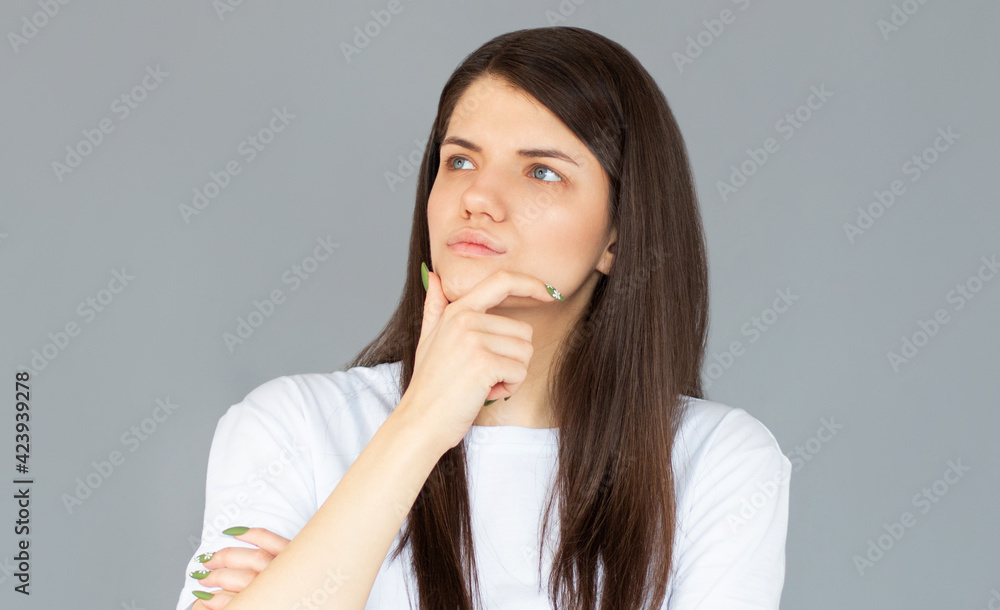 Thoughtful model in studio looking away. hand near the face. isolated gray background Thoughtful model in studio looking away. hand near the face. isolated gray background