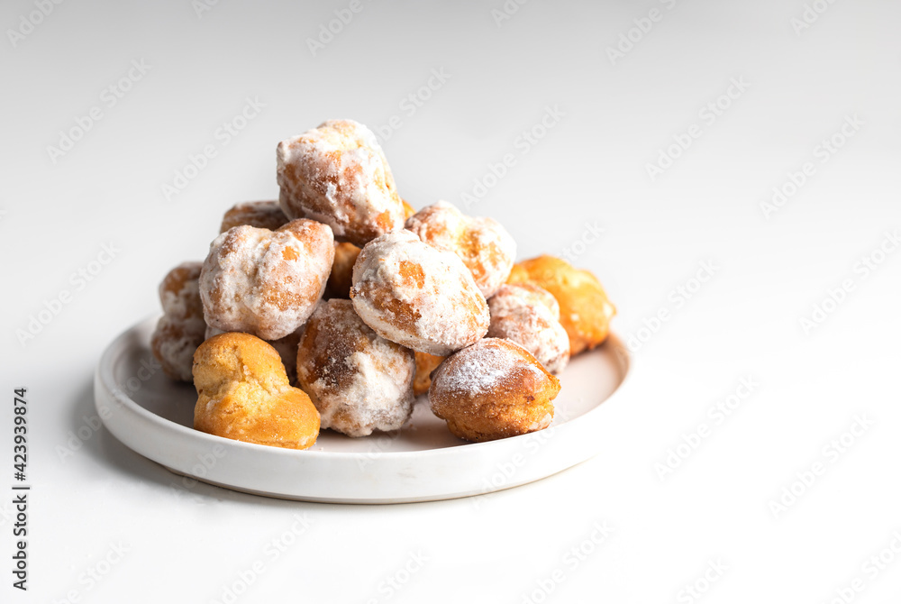 Small deep fried doughs on trhe plate with sugar. Spanish Bonuelos de viento background. Small deep fried doughs on trhe plate with sugar. Spanish Bonuelos de viento background.