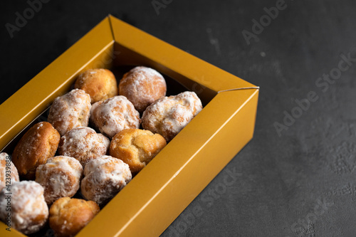 Bunuelos,  small sweet deep fried doughs in the box on dakr background. photo