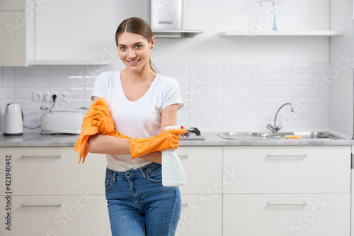 Smiling young woman preparing for cleaning kitchen.