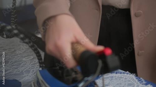 Siview tilt down medium shot of female tailor steaming lace preparing it for sewing standing at ironing board in workshop. professional iron steamer photo