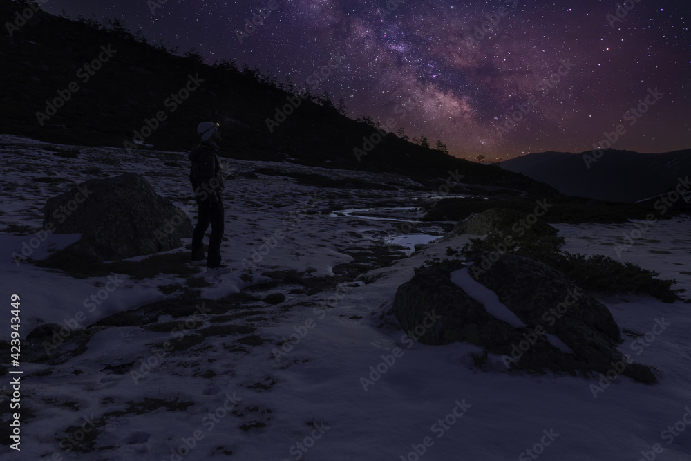 landscape with snow and the milky way in the mountains with a unrecognized person