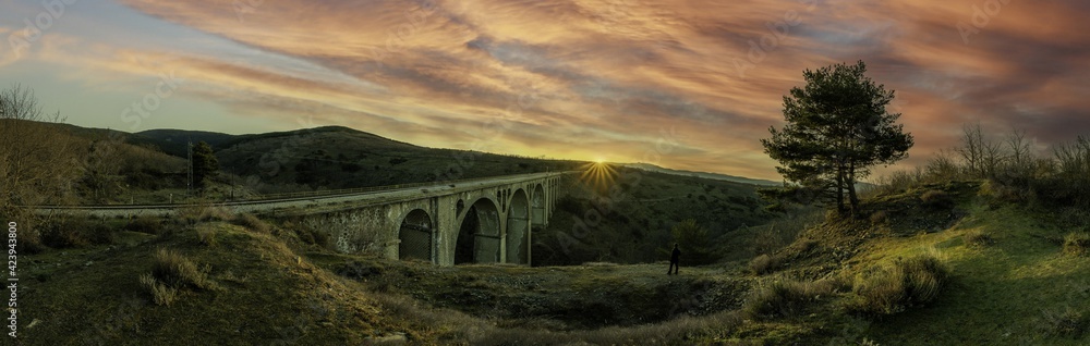 sunrise over the bridge with a yellow sky with clouds in a panoramic photo in the golden hour