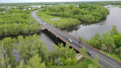 Copter flies over the bridge over the river, cars go