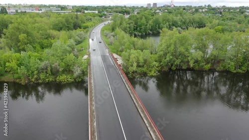 Copter flies over the bridge over the river, cars go
