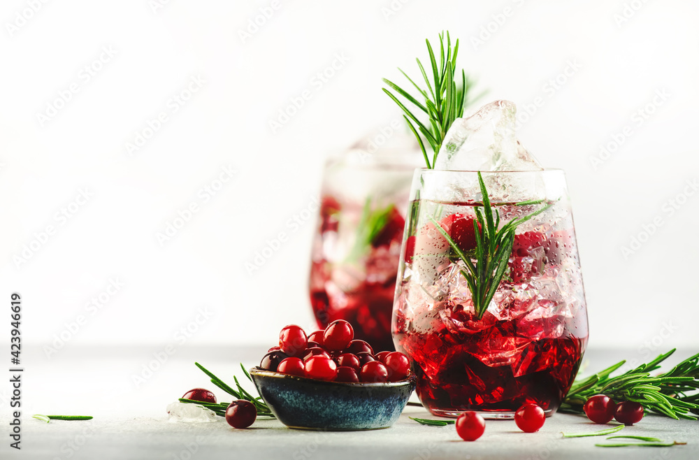 Cranberry cocktail or mocktail with ice, rosemary and red berries in tumbler glass, gray background, copy space Cranberry cocktail or mocktail with ice, rosemary and red berries in tumbler glass, gray background, copy space