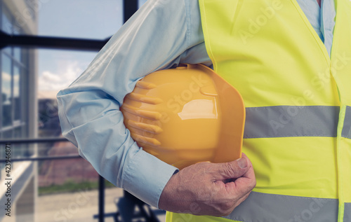 Close-up of old builder holding yellow safety hardhat