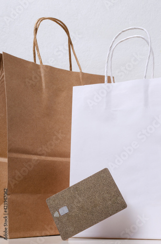 Vertical image f whote and brown craft shopping bags and golden gredit card