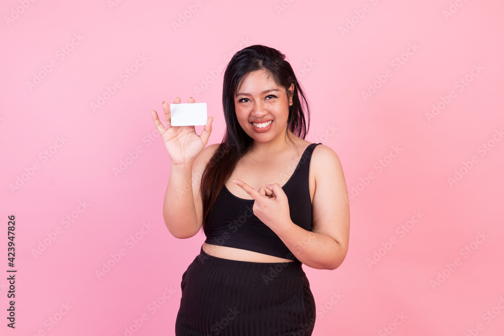 Obese female pointing at white card. Happy Overweight woman standing in pink background. Obese fat woman, plus size fashion model, fat woman on pink background.