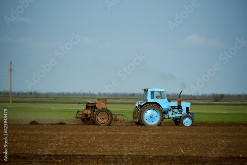 Blue tractor cultivating soil in spring,agriculture industry photo