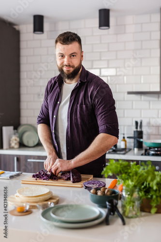 Young Man slicing Vegetables on Cutting board and cooking fresh and healthy food at home in cozy kitchen  copy space  food commercial