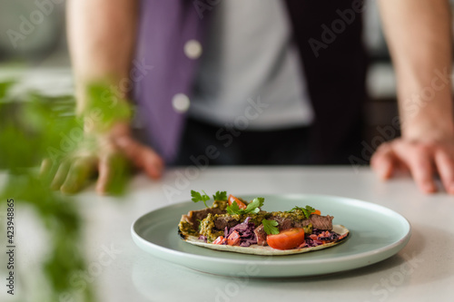 Fototapeta Naklejka Na Ścianę i Meble -  Close Up Mexican food tacos presentation on white table at home in modern kitchen with chef in Background, Fresh Food Homemade Styling Presentation, Copy Space