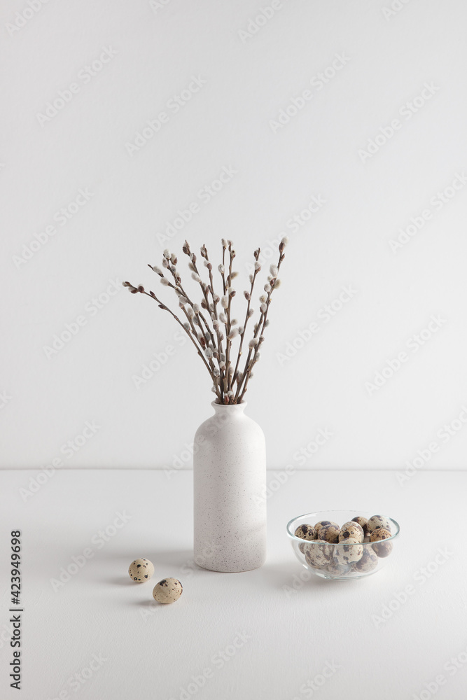 Easter eggs in bowl and willow bouquet on white background, space for text. Vertical frame.