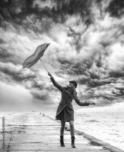 A girl with umbrella in stormy weather on the pier. Black and white. photo