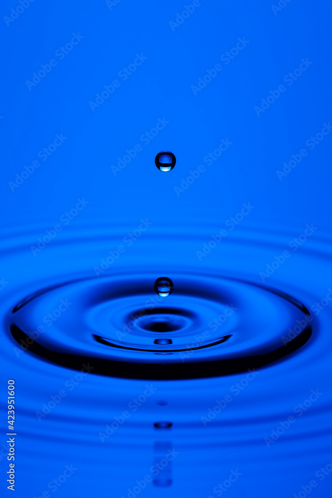 Close-up Shot of Two Blue Water Droplets On Tranquil Water Surface. Close-up Shot of Two Blue Water Droplets On Tranquil Water Surface.