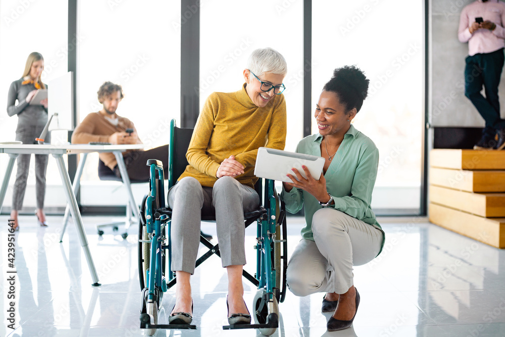 Senior business woman in wheelchair working in office Senior business woman in wheelchair working in office