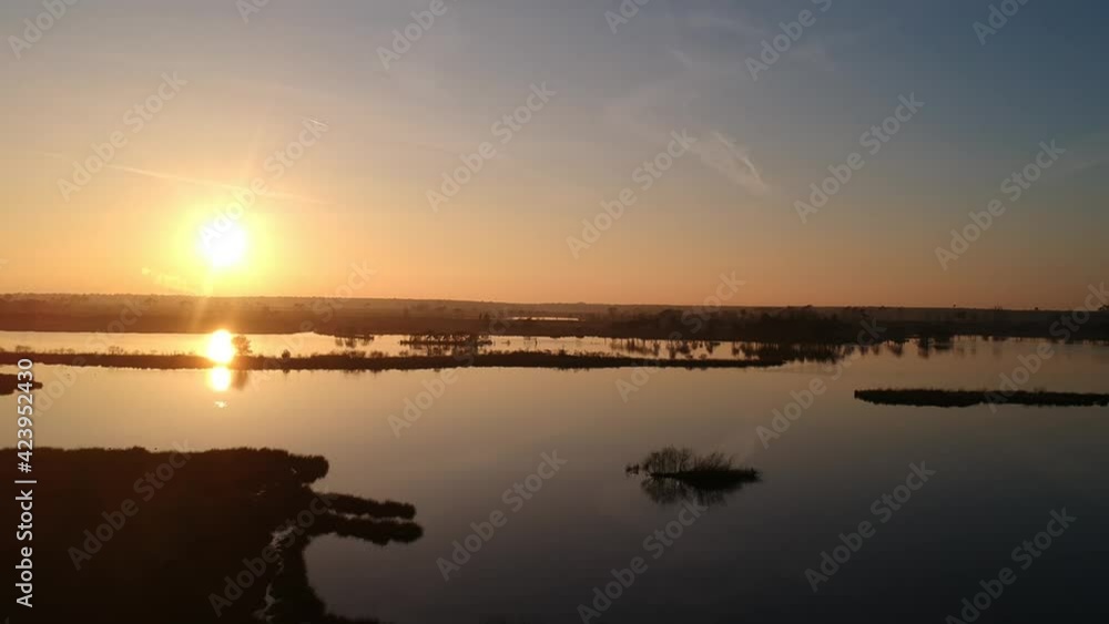 Panning aerial shot sun setting golden hour teal orange sky reflection