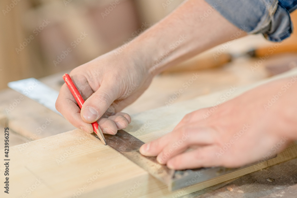 Close up male hands taking measurement of a wooden plank in carpentry workshop Close up male hands taking measurement of a wooden plank in carpentry workshop