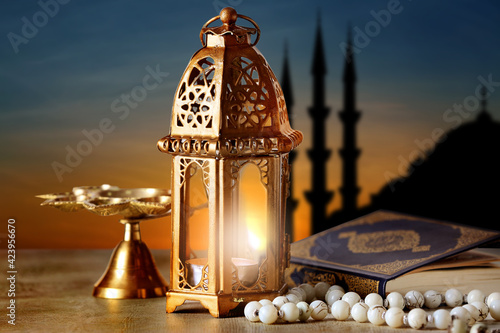 Muslim lamp, tasbih and Koran on table at sunset photo