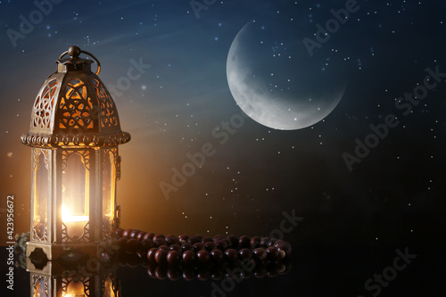 Muslim lamp and tasbih on table against night sky