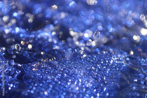 Wallpapers. Frozen movement of water. Drops of water falling and splashing. Sparkles, reflections of light. Vibrant blue color. 