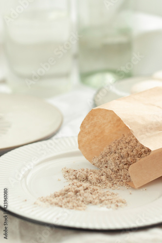 Hazelnut flour. Walnut flour in a paper bag on a light plate with French pastries macaroons in pastel light colors. Ingredients for a pastry shop and bakery