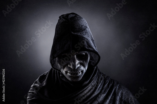 Scary figure with hooded cape in the dark