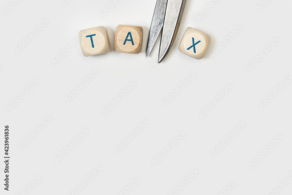 La palabra reducción de impuestos TAX escrita en cubos de madera junto a una tijera sobre un fondo gris claro. Vista superior. Copy space. Concepto de reducción, reducción o deducción de impuestos. La palabra reducción de impuestos TAX escrita en cubos de madera junto a una tijera sobre un fondo gris claro. Vista superior. Copy space. Concepto de reducción, reducción o deducción de impuestos.
