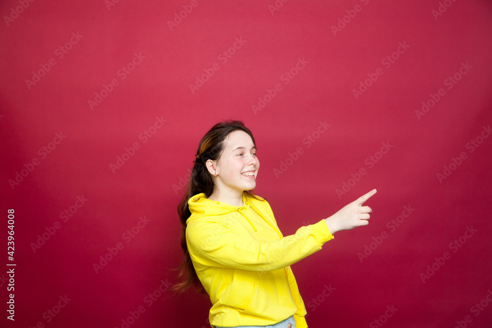Portrait of beautiful young girl in yellow hoodie against red Portrait of beautiful young girl in yellow hoodie against red