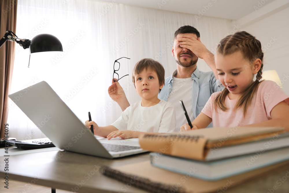 Overwhelmed man combining parenting and work at home Overwhelmed man combining parenting and work at home