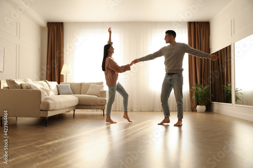 Fototapeta Naklejka Na Ścianę i Meble -  Happy couple dancing barefoot in living room. Floor heating system