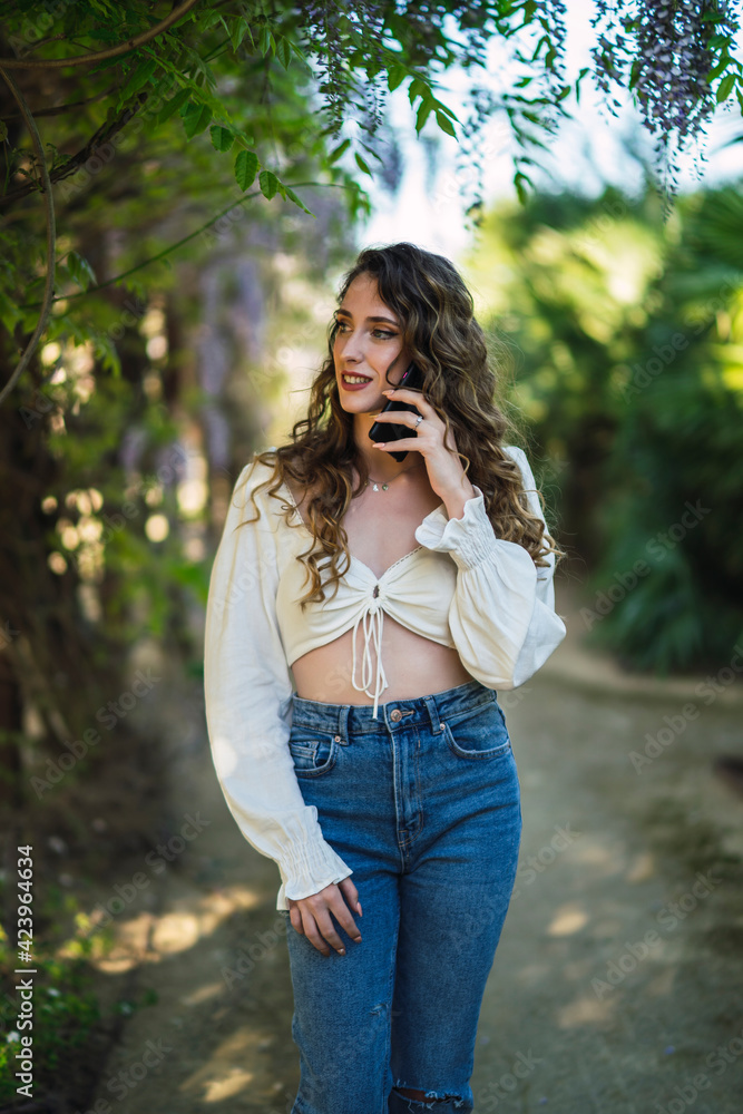 Chica joven guapa en un parque usando el smartphone y dando un paseo en primavera Chica joven guapa en un parque usando el smartphone y dando un paseo en primavera