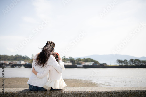 座って海を見る母と娘