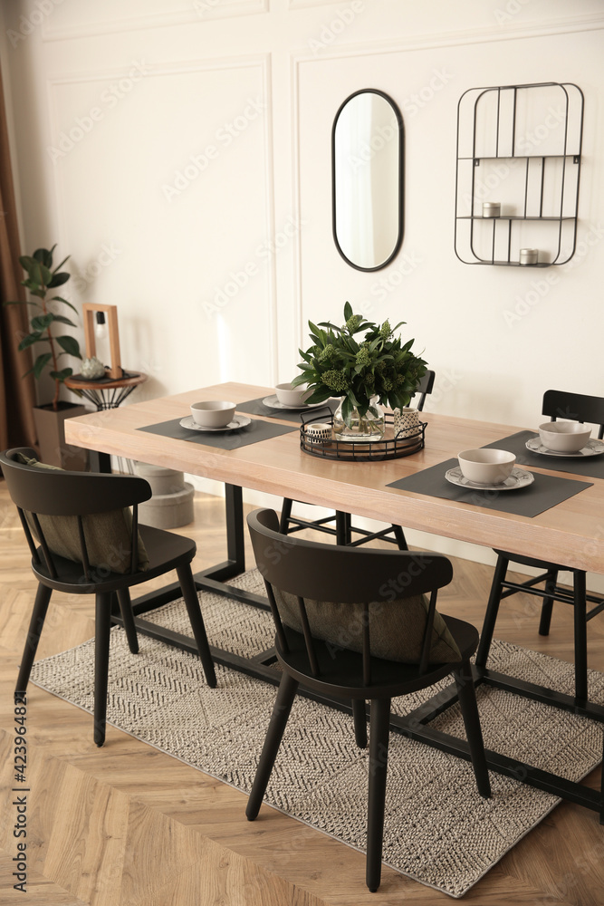 Stylish wooden dining table and chairs in room. Interior design Stylish wooden dining table and chairs in room. Interior design
