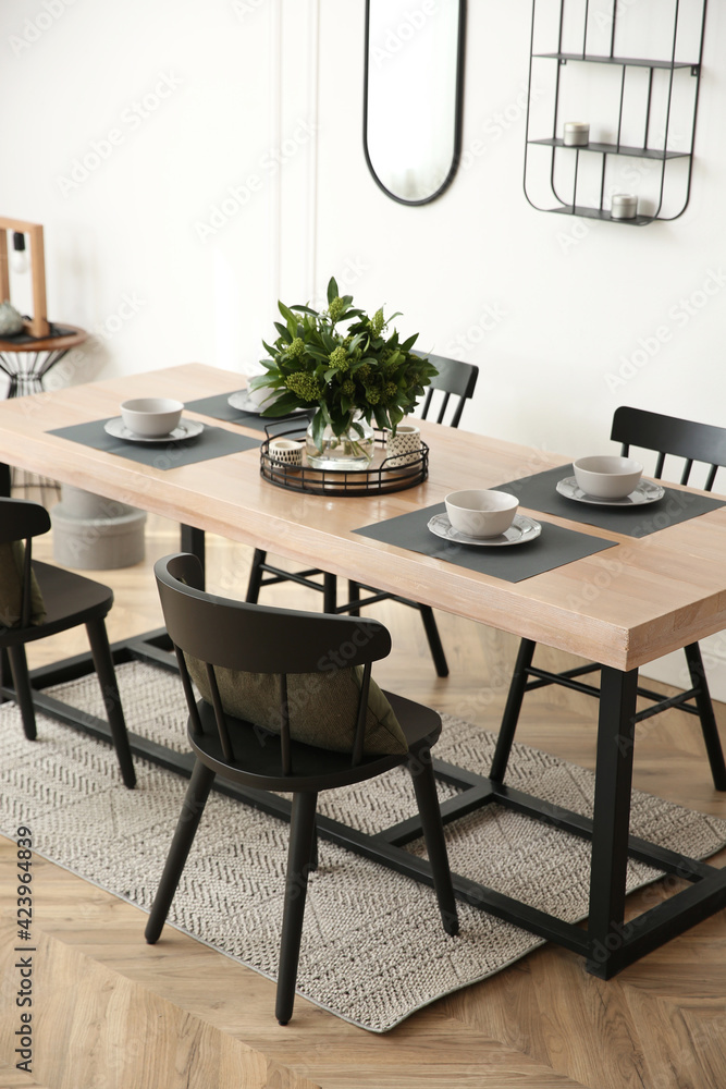 Stylish wooden dining table and chairs in room. Interior design Stylish wooden dining table and chairs in room. Interior design