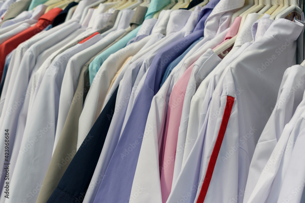 A row of clothes hanging tightly on hangers. White and colored shirt. Clothing store concept. A row of clothes hanging tightly on hangers. White and colored shirt. Clothing store concept.