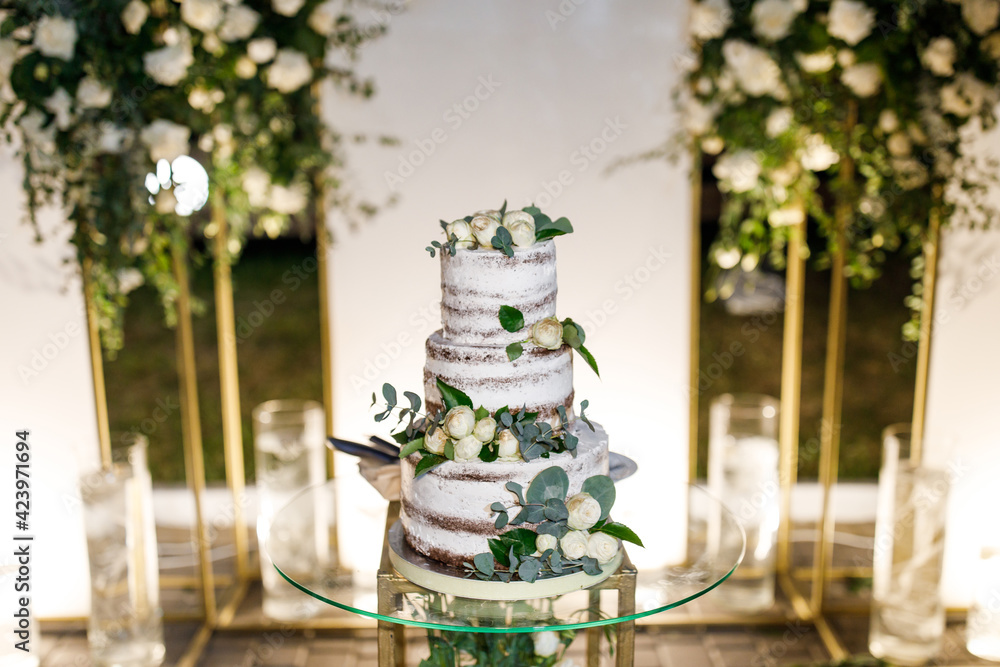 Beautiful delicious white wedding cake at the evening. Wedding cake for guests and brides