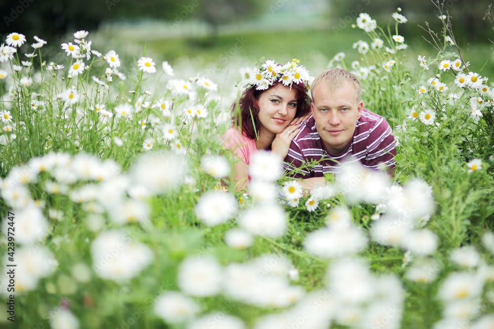 Couple in love guy and girl in a field of white daisies and green grass Couple in love guy and girl in a field of white daisies and green grass