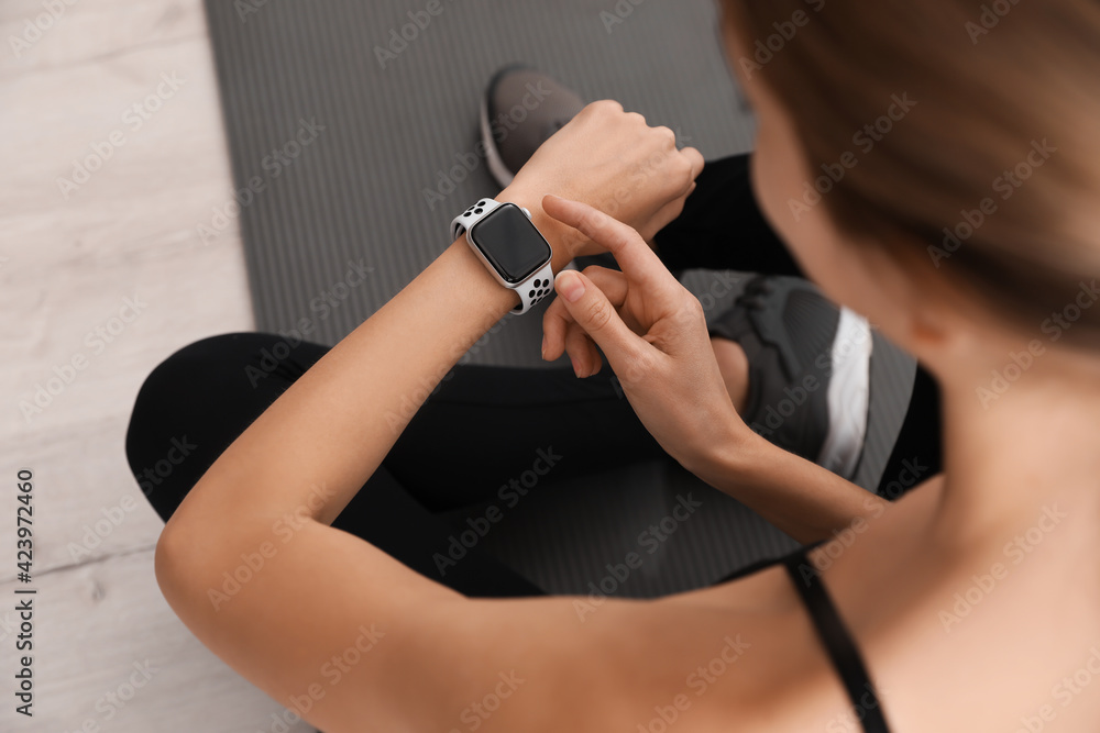 Young woman using smart watch during training indoors, closeup