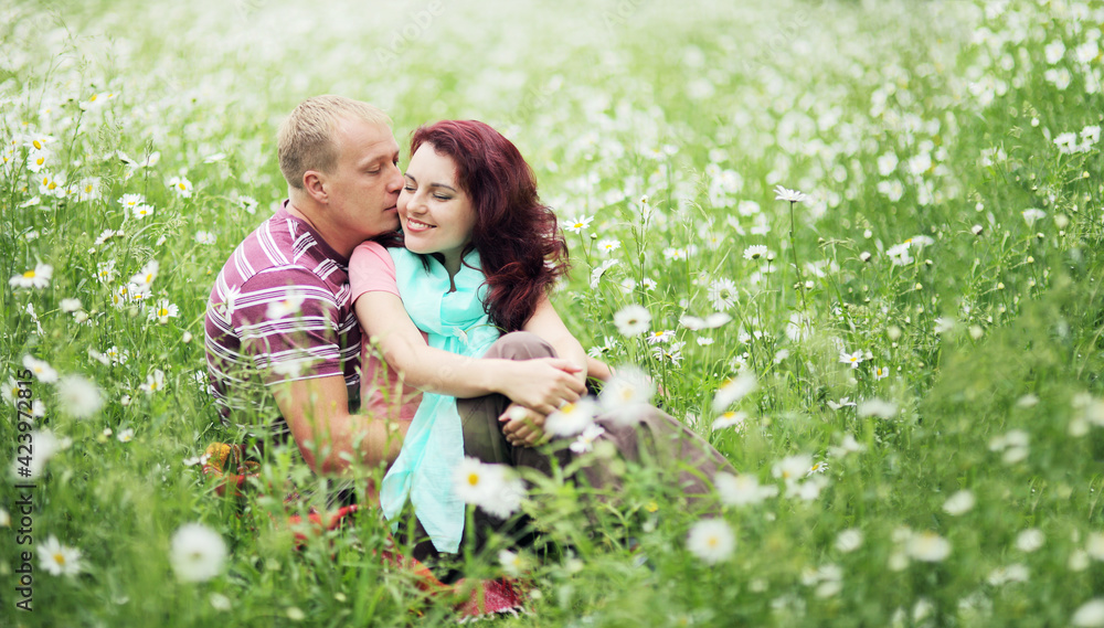 Fototapeta premium Couple in love guy and girl in a field of white daisies and green grass