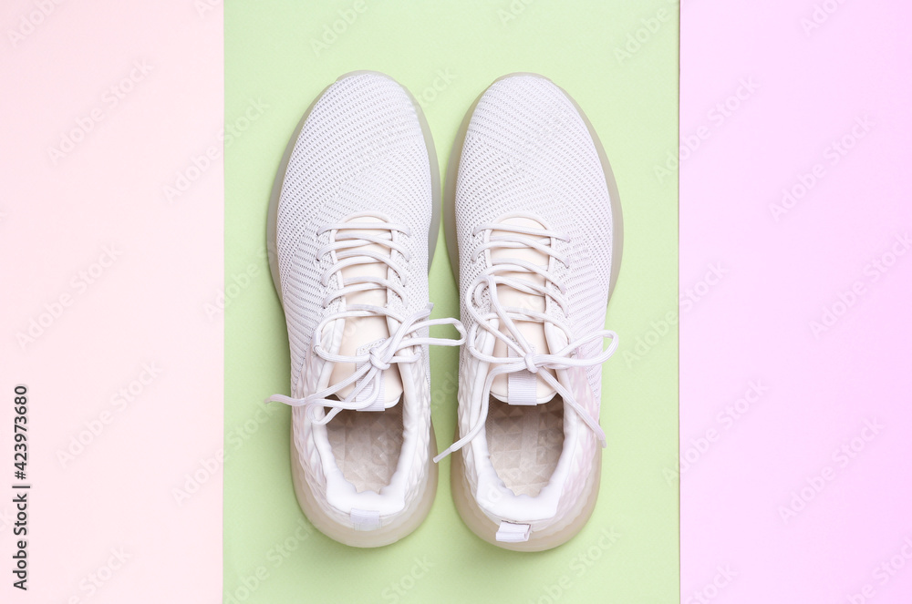 Stylish sporty sneakers on color background, top view