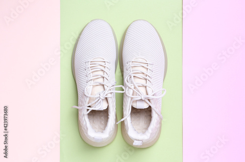 Stylish sporty sneakers on color background, top view