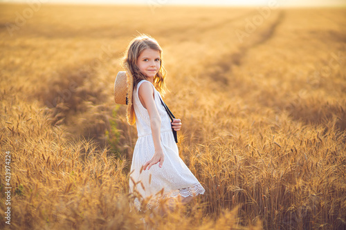 Little girl walking in white dress walk on sunset field