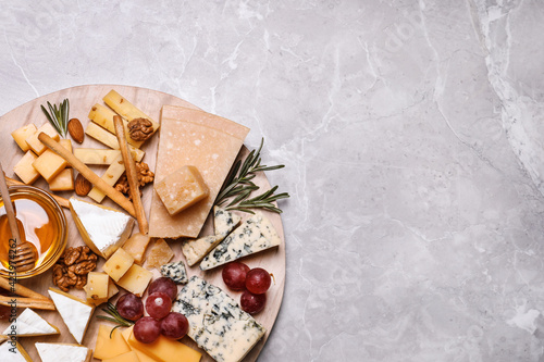 Cheese plate with honey, grapes and nuts on light grey marble table, top view. Space for text