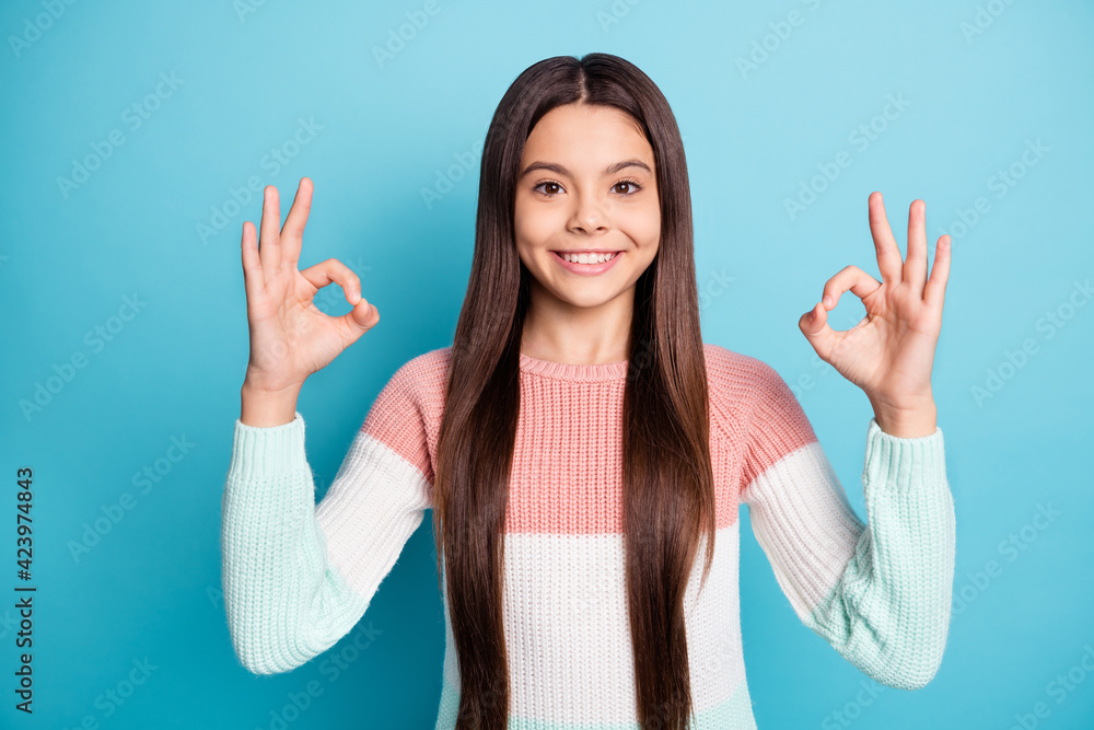 Photo of young girl happy positive smile show okey sign alright ad recommend great feedback isolated over blue color background Photo of young girl happy positive smile show okey sign alright ad recommend great feedback isolated over blue color background