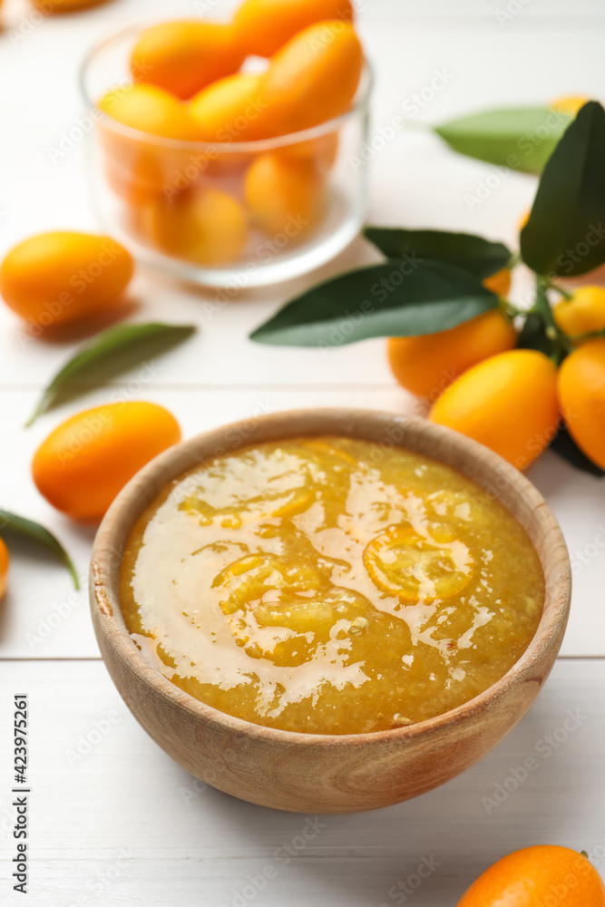 Delicious kumquat jam in bowl and fresh fruits on white wooden table Delicious kumquat jam in bowl and fresh fruits on white wooden table