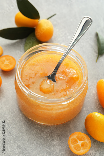 Delicious kumquat jam and fresh fruits on light grey table