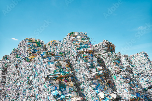 Big pressed cubes of plastic bottles waste and rubbish at blue skies background outdoors.