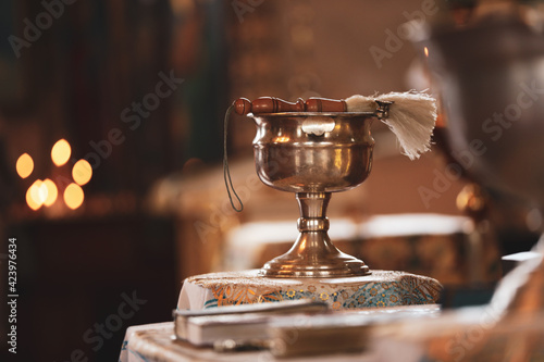 Silver vessel with holy water and brush on stand in church, space for text. Baptism ceremony
